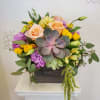 Mixed bouquet with roses, lisianthus, and a succulent in a dark box