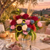 Mixed bouquet of roses, carnations, and sunflowers in a glass vase on a table