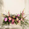 Low floral arrangement of pink and peach roses in a wooden box