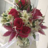 Bouquet of pink roses and lilies in a glass vase with white ribbon