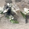 White orchid corsages with black ribbon bows on a wood surface