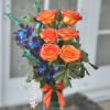 Orange roses with blue orchids in a glass vase