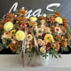 Large mixed floral arrangement in a round box with tan and yellow blooms