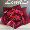 Large bouquet of red and pink roses wrapped in burgundy paper