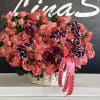 Pink rose bouquet with dark purple orchids in a white basket