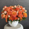Orange and peach roses arranged in a white vase