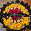 Bouquet of yellow and red roses with gold chocolates and a black ribbon