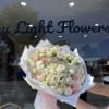 Large bouquet of white and blush roses wrapped in white paper with a pink ribbon