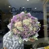 Large bouquet of lavender and cream roses wrapped in purple paper