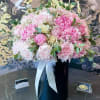 Pink peony and rose bouquet in a black vase with white ribbon