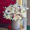 Round bouquet of white and blush roses in a gray hatbox