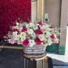 Large mixed rose arrangement in a woven basket on a stand