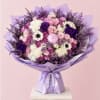 Lavender and pink bouquet with roses, hydrangeas, and white anemones in purple wrap