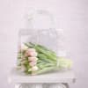A wrapped bouquet of pale pink tulips in a clear gift bag