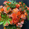 Bouquet of orange and peach roses with glossy green foliage