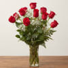 Red roses arranged in a clear glass vase with white baby's breath