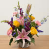 Mixed bouquet with pink lilies, yellow roses, and purple flowers in a woven basket