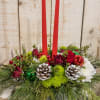 Holiday centerpiece with red candles, roses, and pinecones