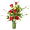 Red roses arranged in a tall glass vase with eucalyptus