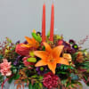 Bright floral arrangement with orange lilies and two red candles