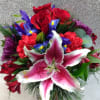 Bouquet of red roses, pink lilies, and purple flowers in a glass vase