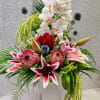 Tall floral arrangement with white orchids, red roses, and pink lilies in a white vase