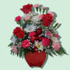 Red and pink flower arrangement in a red smiling pot