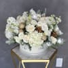 White floral arrangement with roses and hydrangeas in a round box
