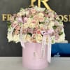 Pink and cream roses arranged in a pastel pink box with ribbon