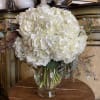White hydrangea bouquet in a clear glass vase with eucalyptus accents