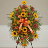Standing floral spray with sunflowers, orange roses, and a ribbon bow