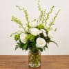 White roses and green blooms arranged in a clear glass vase