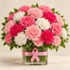 Pink and white carnations in a glass vase with a pink ribbon