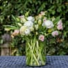 White and pale pink flowers arranged in a clear glass vase