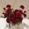 Red roses arranged in a clear glass vase with a black ribbon
