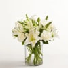 White roses and lilies arranged in a clear glass vase