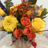 Bouquet of yellow and orange roses with chrysanthemums in a pumpkin vase