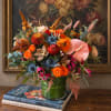 Colorful mixed flower arrangement in a green glass vase