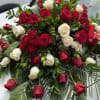 Red and white roses arranged with greenery and palm fronds