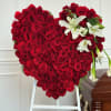 Heart-shaped arrangement of red roses with white lilies on a stand