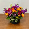 Colorful mixed flower arrangement in a black round box