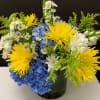 Yellow and white flowers with blue hydrangeas in a green vase