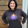 Person wearing a black hoodie with a purple and yellow flower graphic