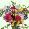 Mixed bouquet of roses, lavender blooms, and blue grape hyacinth in a glass vase