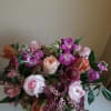 Low pink and purple flower arrangement with roses and tulips in a clear glass vase