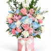 Pastel bouquet of roses, carnations, and filler flowers in a pink hatbox with a bow