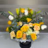 Yellow roses, white lilies, and carnations in a black hatbox