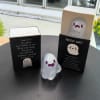 Small ghost figurines in black gift boxes on a table