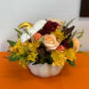 Mixed bouquet in a white pumpkin-shaped vase with peach roses and yellow mums