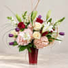 Mixed bouquet of roses, lilies, hydrangeas, and tulips in a red vase